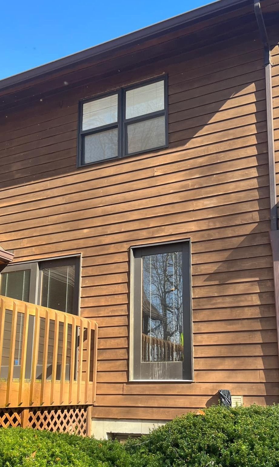 A house with a wooden deck and a lot of windows.