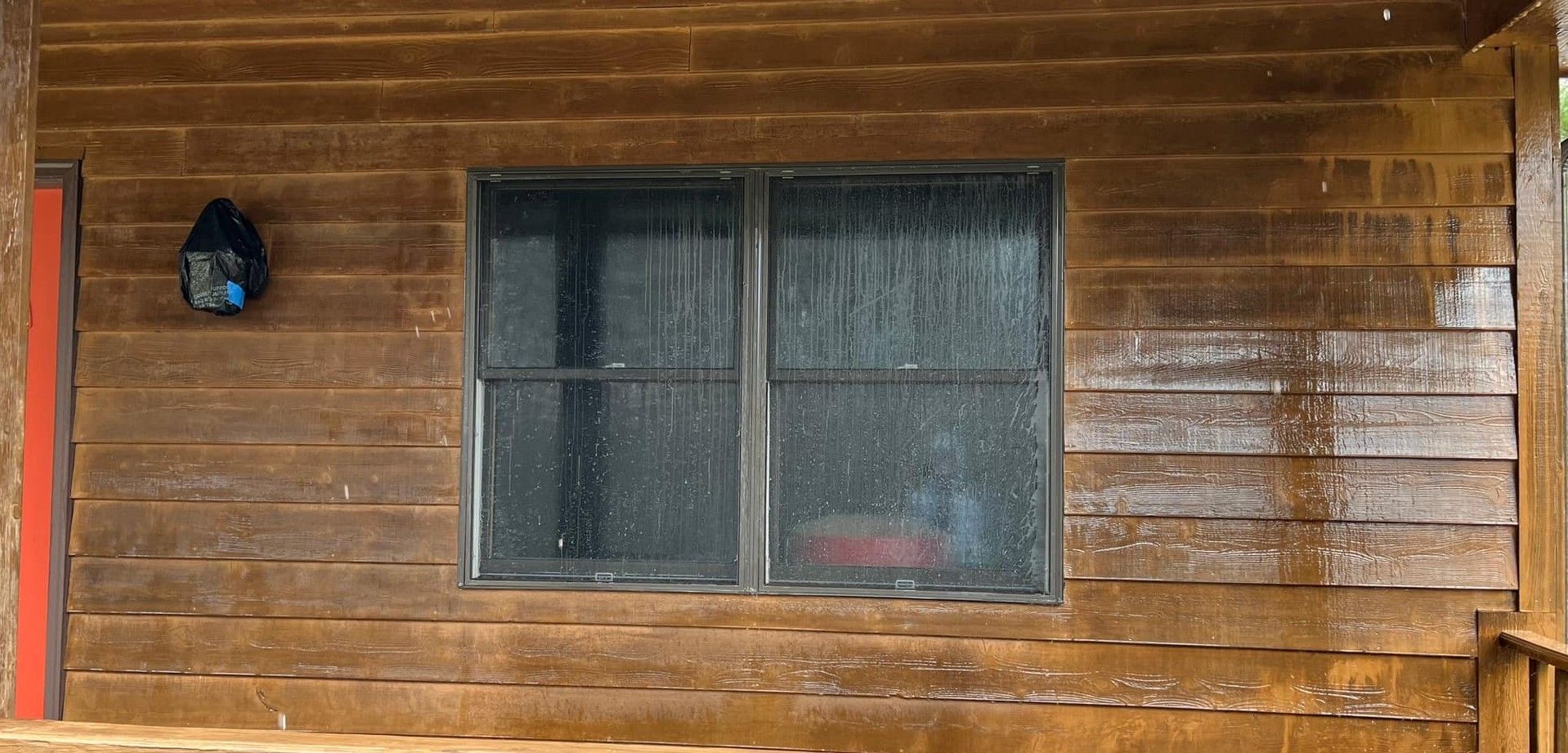 A wooden house with a window and a red door.