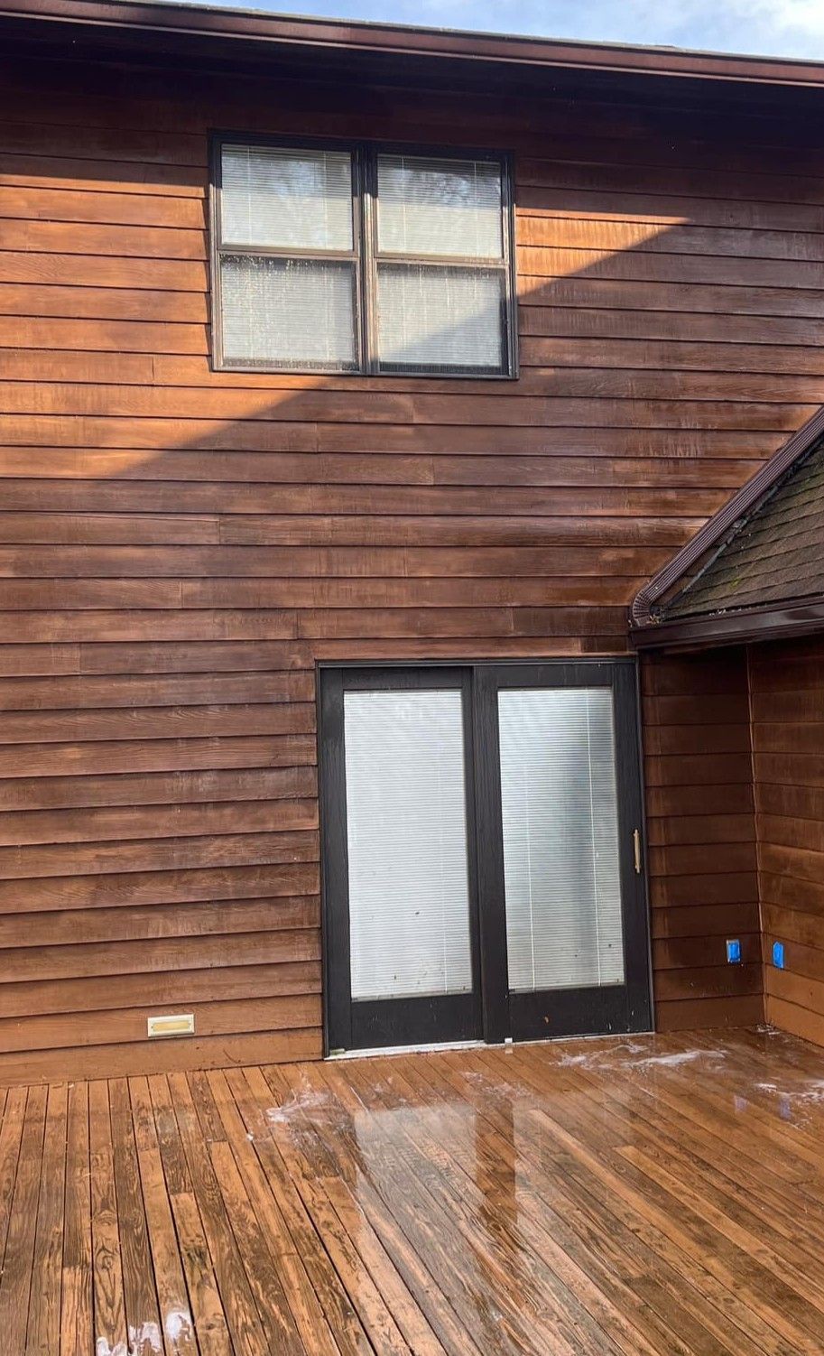 A wooden house with a sliding glass door and a wooden deck.