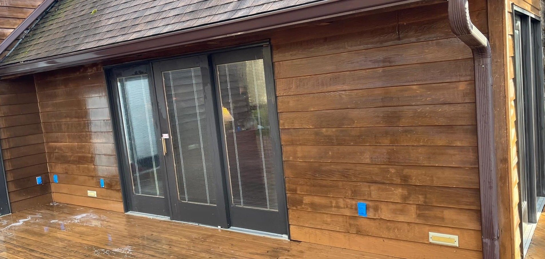 A wooden house with sliding glass doors and a roof.