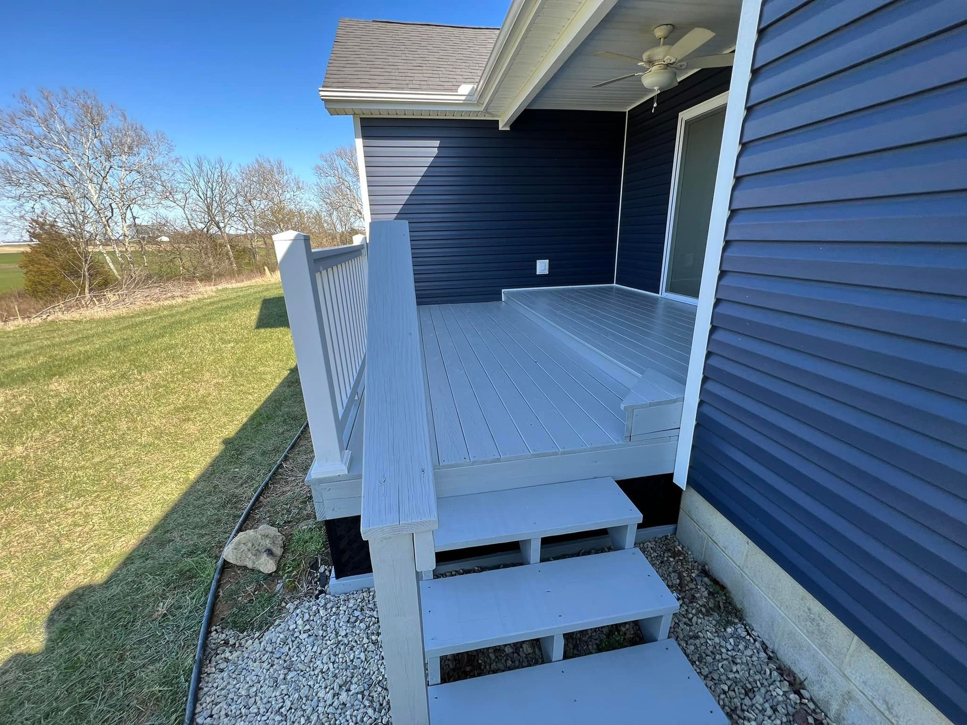 A blue house with a deck and stairs on the side of it.