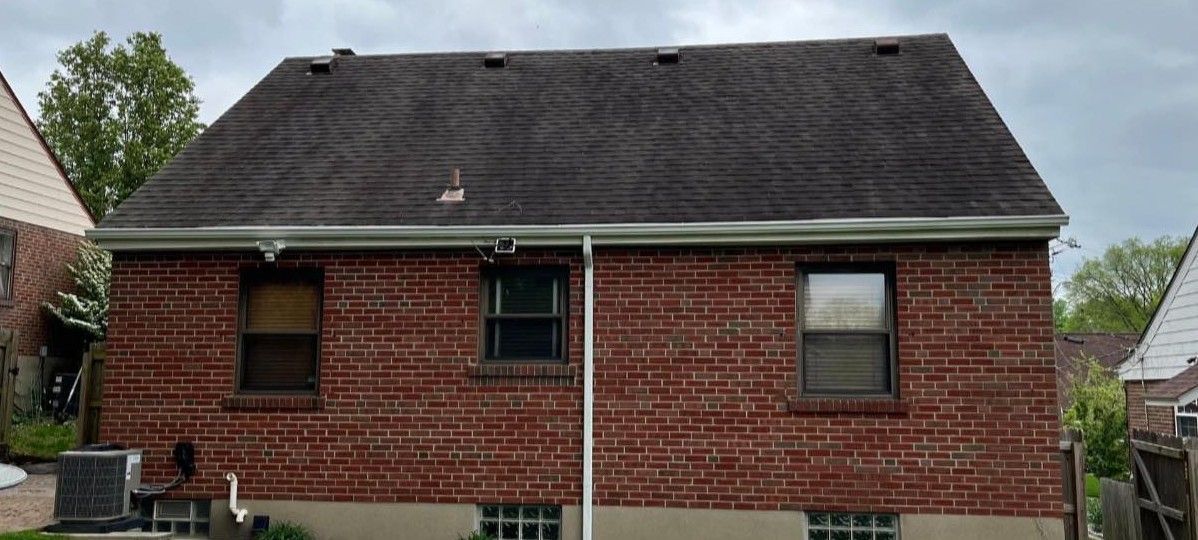 The back of a brick house with a black roof.