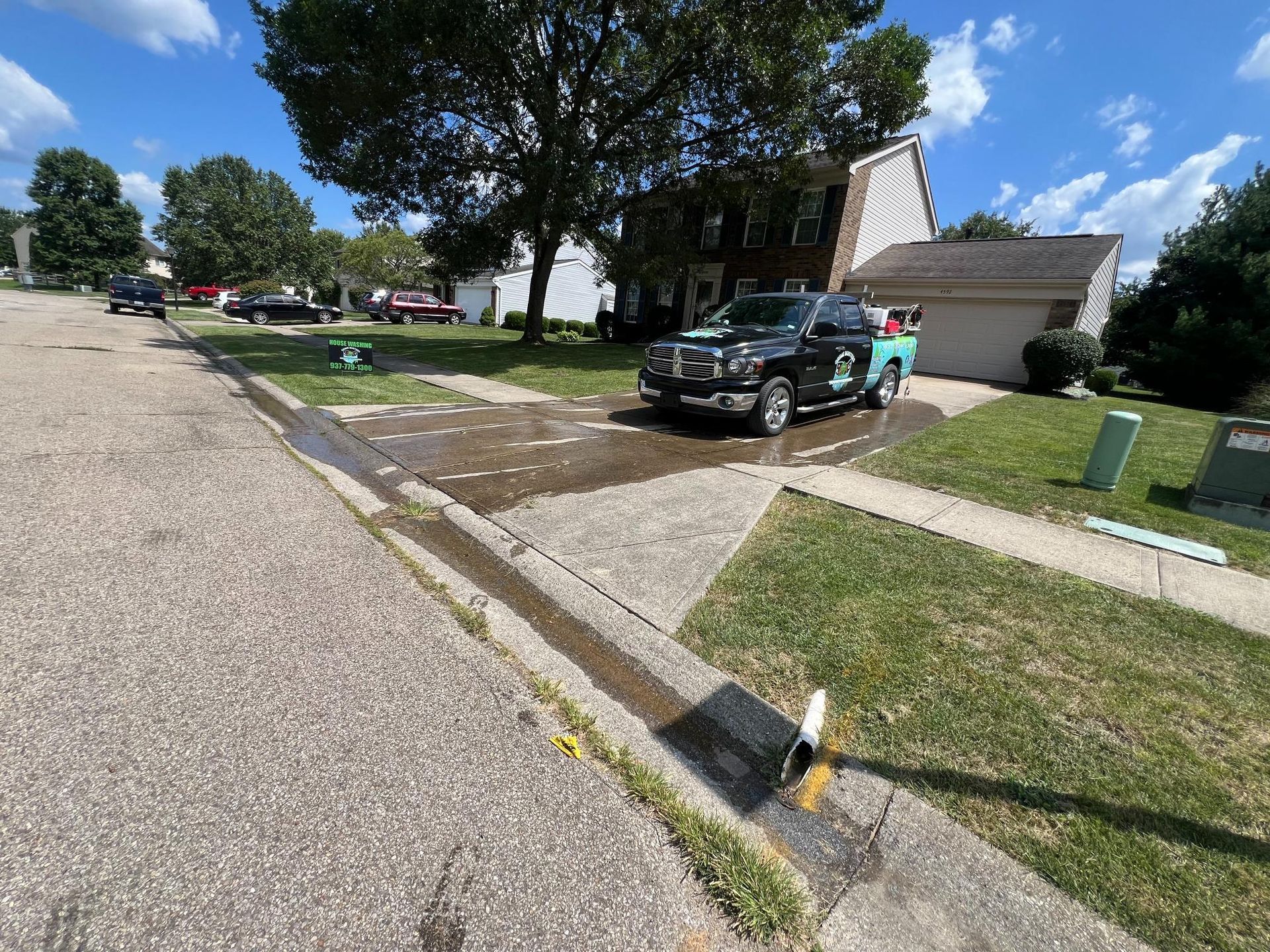 Suburban street with parked truck, driveway, lawns, and a black-and-yellow fire hydrant by the curb