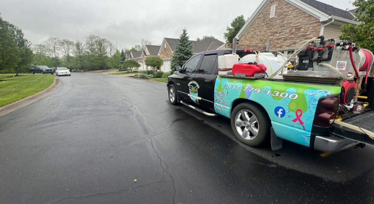 Decorated black pickup truck on a wet suburban street, carrying colorful items in the bed.