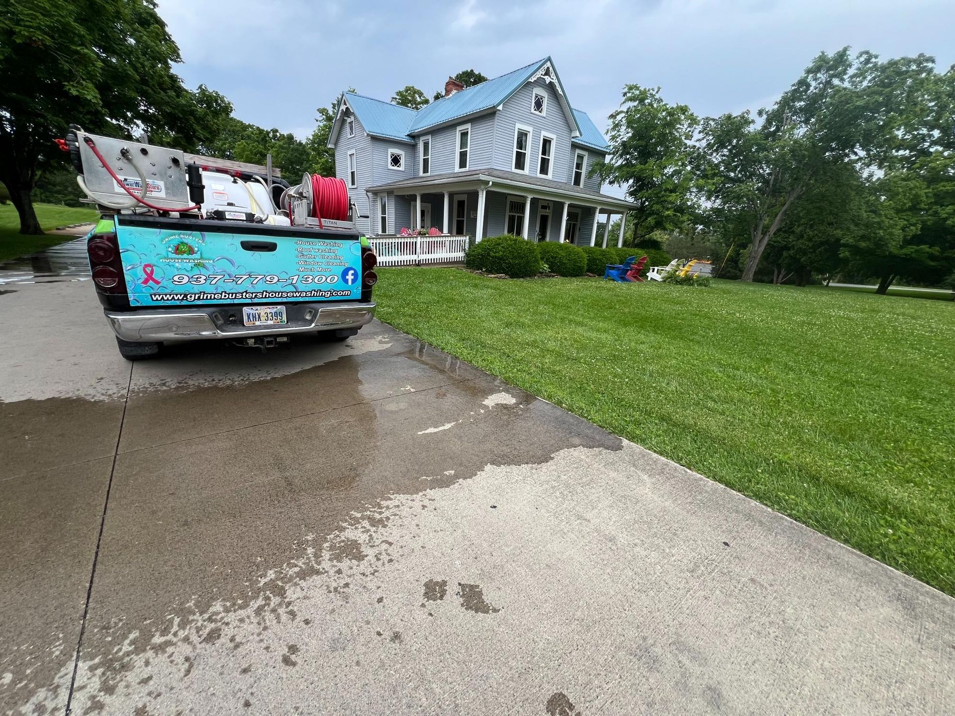 Pickup truck hauling debris outside a blue house with a large green lawn
