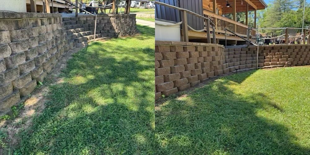 Stone retaining wall beside a grassy backyard slope with brown block steps and a wooden deck above