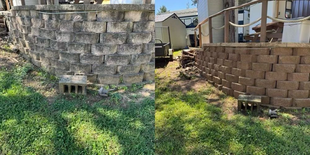 Backyard with stacked concrete blocks, a stone retaining wall, and overgrown grass in sunlight