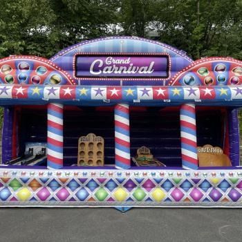 A vibrant inflatable carnival booth with red, white, and blue stripes and game stations set up for play.