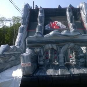 An inflatable obstacle course slide with a gray, rock-like pattern and an 