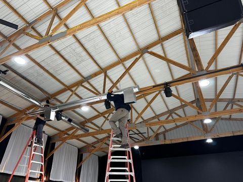 Exposed silver HVAC ductwork suspended from an industrial ceiling in an unfinished room with metal shelving.