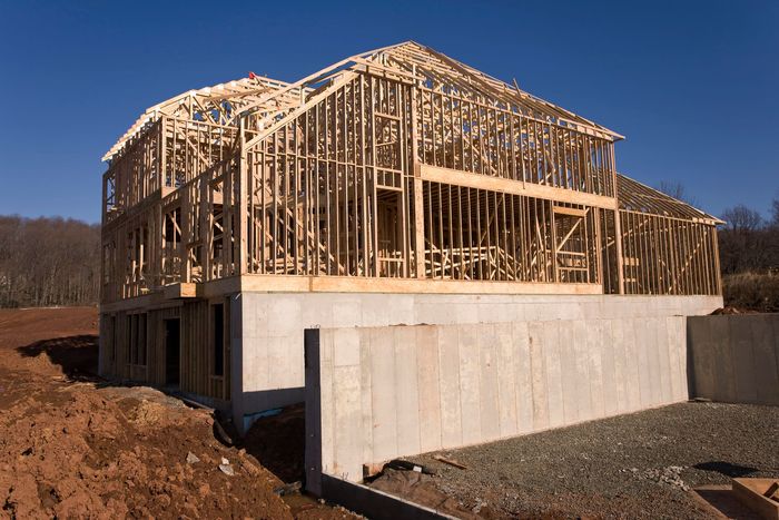A construction worker is standing in an empty building looking at a tablet. A construction worker is standing in an empty building looking at a tablet.