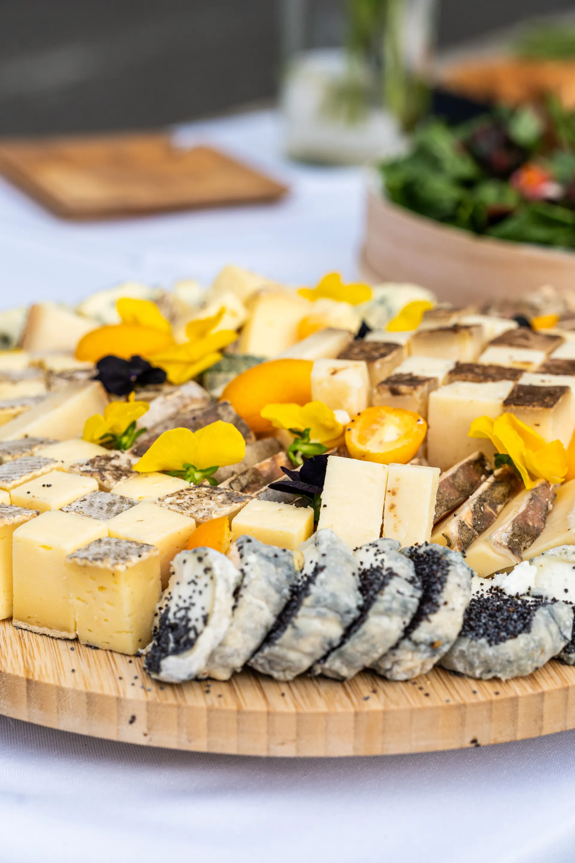 Plateau de fromages assortis avec fruits et fleurs sur une planche en bois à table