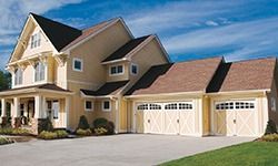 A large house with three garage doors and a large driveway.
