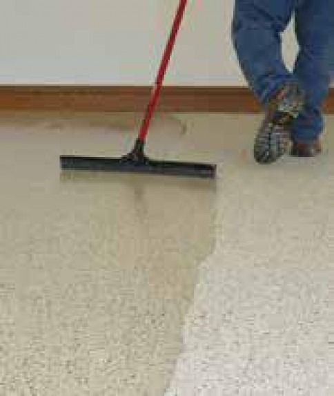 A person is using a broom to clean a floor.