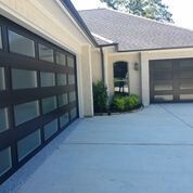 A garage door with a lot of windows is in front of a house.