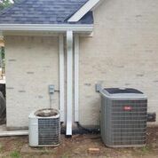 There are two air conditioners on the side of a house.
