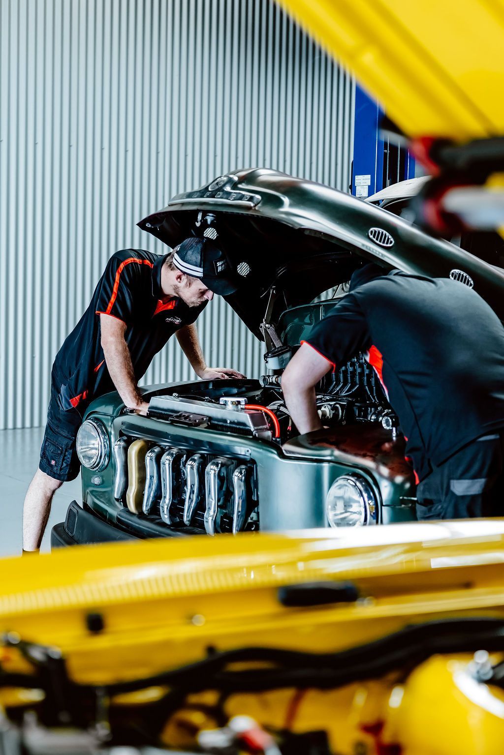 Mechanic inspecting car engine in garage with hood open, yellow car body in foreground — Mechanic in Wollongong, NSW