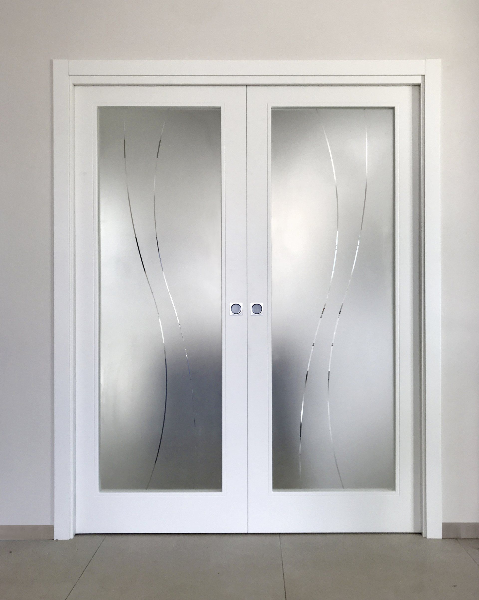 Doppie porte bianche con pannelli in vetro satinato decorati con delicati motivi astratti a linee curve verticali.