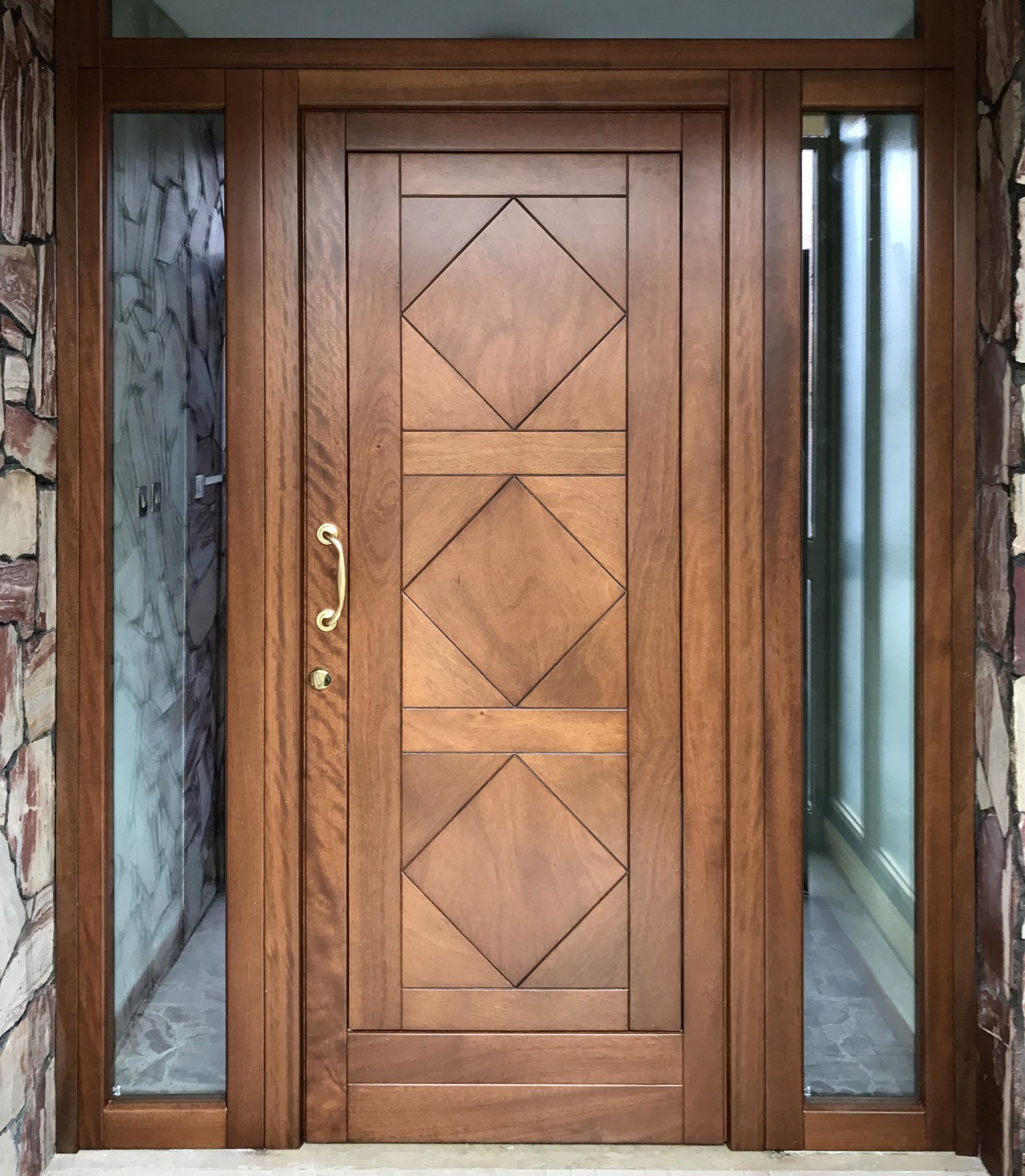 Una porta d'ingresso in legno con tre pannelli incassati a forma di diamante