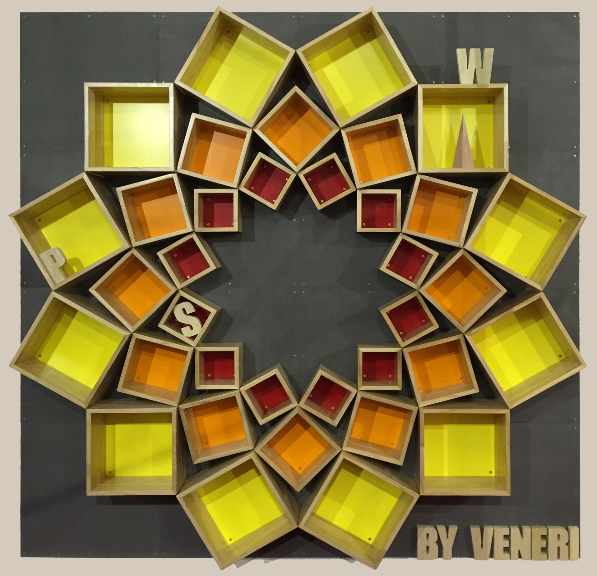 Un'installazione geometrica a parete composta da mensole disposte a raggiera, con scatole di legno nelle tonalità del giallo e del rosso.