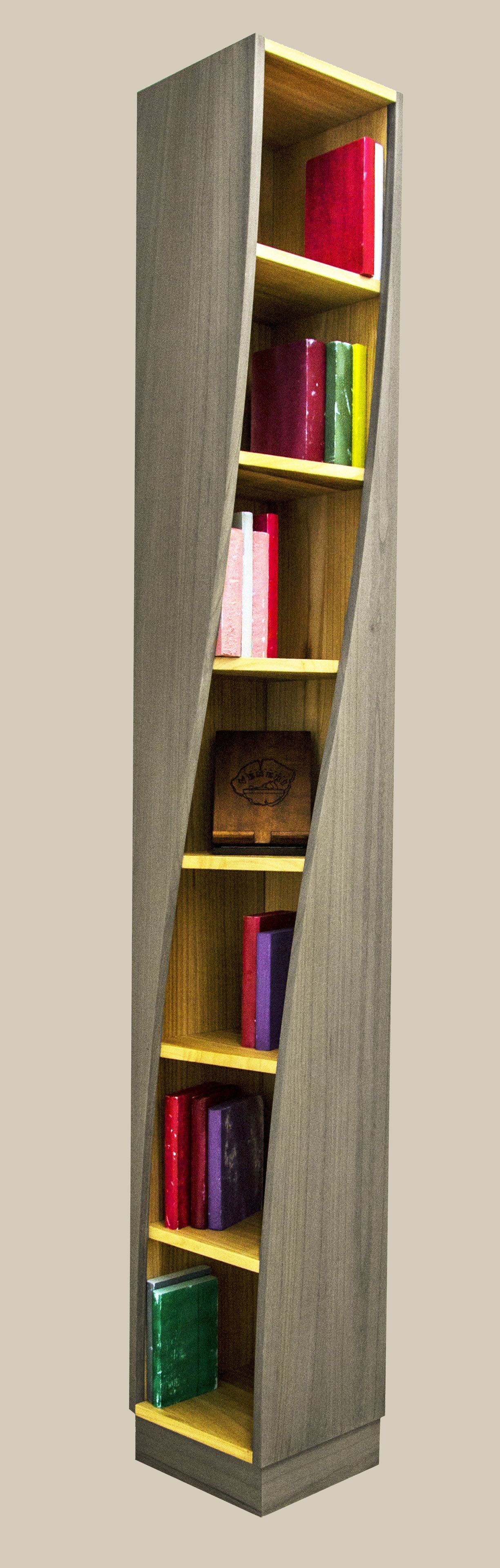 Una libreria alta, stretta e contorta, con ripiani in legno e lati grigi dalla texture particolare, piena di libri di vario genere e dai colori vivaci.