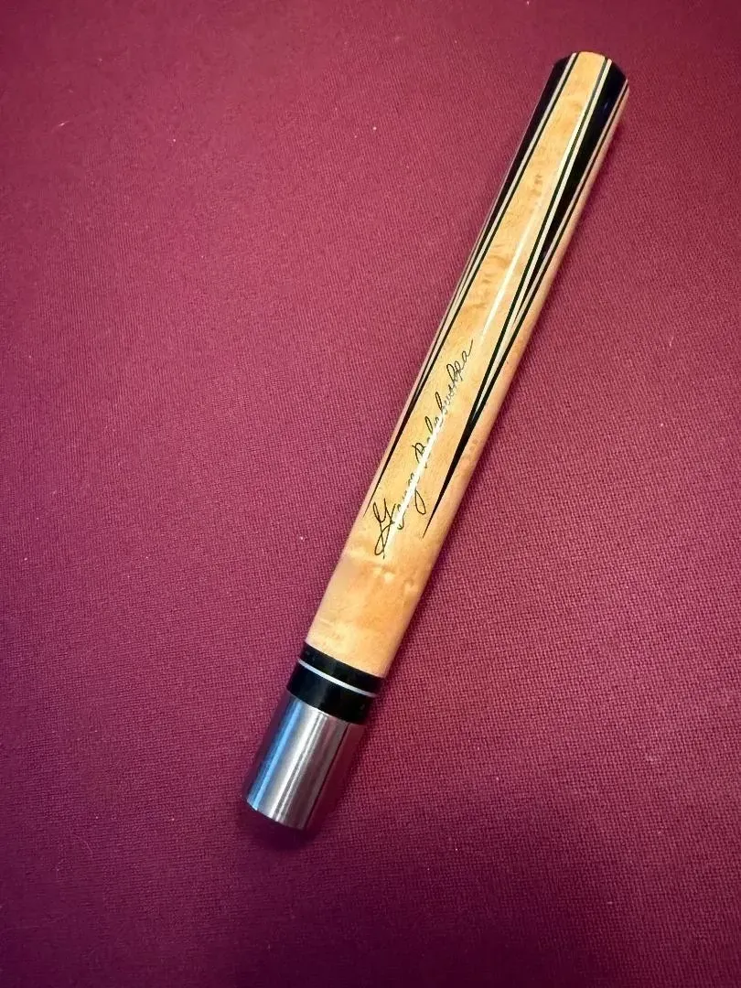 Wooden pen with a metal cap on a red textured background