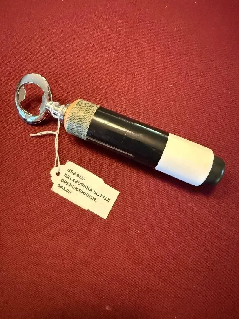 Black and white cylindrical keychain flashlight with a ring and tag on a red fabric surface