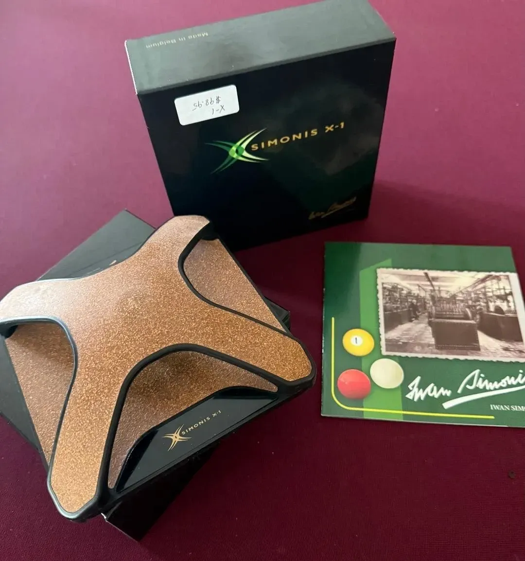 Three boxed decorative items: a black box, a green square box, and a copper star-shaped object on a pink surface