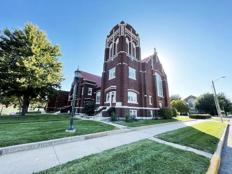 A large red brick church with a steeple is sitting on a lush green lawn.