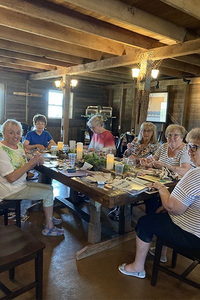 women seated at a table doing crafts