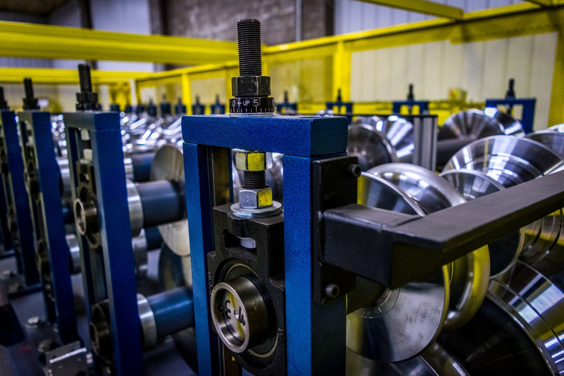 Blue and silver industrial roll forming machine; metal shaping equipment in a factory.