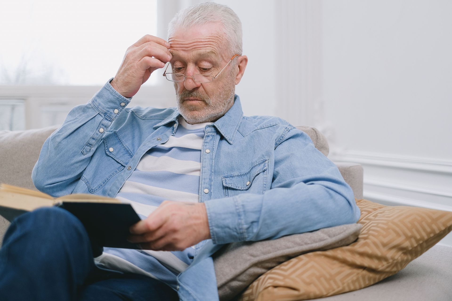 Person experiencing blurry vision while reading due to possible cataract symptoms