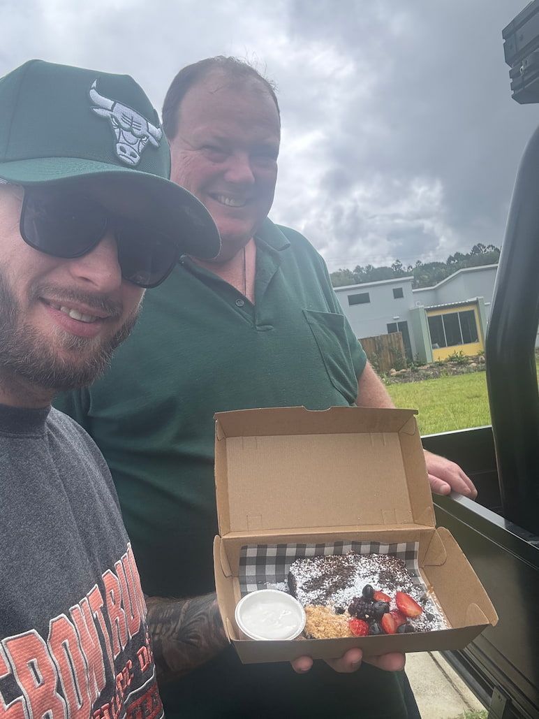 A Man Wearing a Chicago Bulls Hat is Holding a Box of Food — Mentally Hooked in Helensvale, QLD