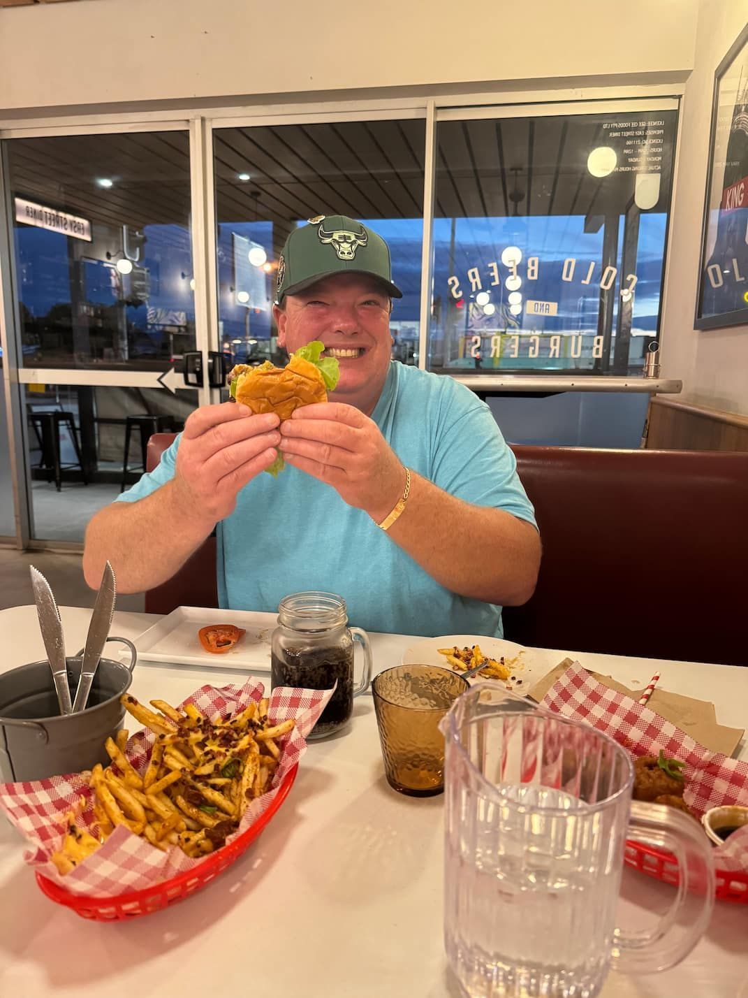 A Man is Sitting at a Table Eating a Hamburger and French Fries — Mentally Hooked in Helensvale, QLD