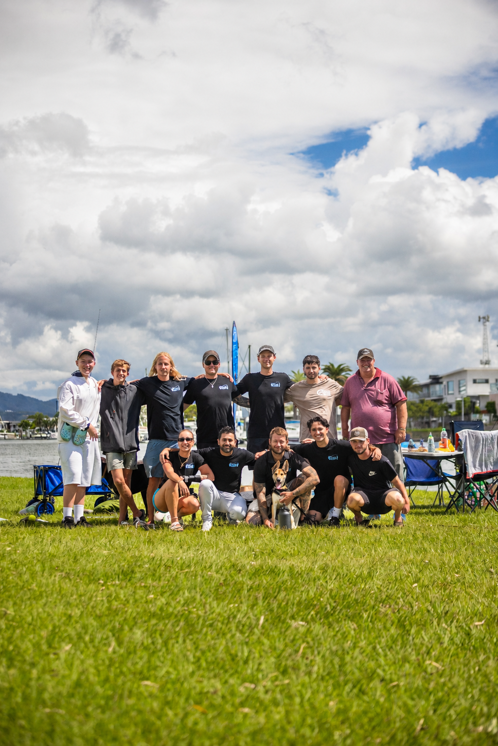 Group posing on a grassy field under cloudy skies, with mountains and tents in the background. — Mentally Hooked in Brisbane, QLD