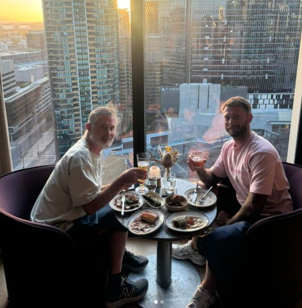 Two Men Are Sitting at a Table With Plates of Food and Drinks — Mentally Hooked in Helensvale, QLD