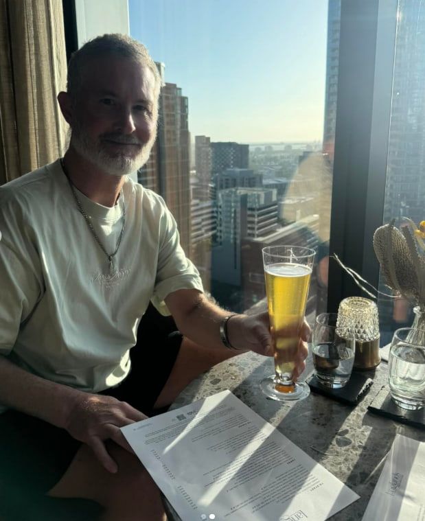 A Man is Sitting at a Table Holding a Glass of Beer — Mentally Hooked in Helensvale, QLD