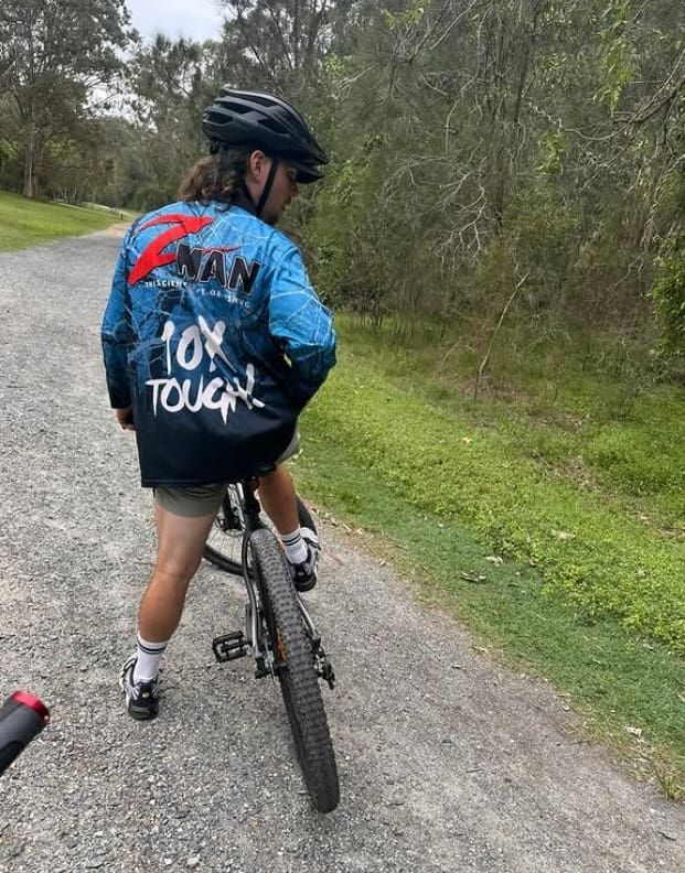 A Person is Riding a Bike Down a Dirt Road — Mentally Hooked in Helensvale, QLD