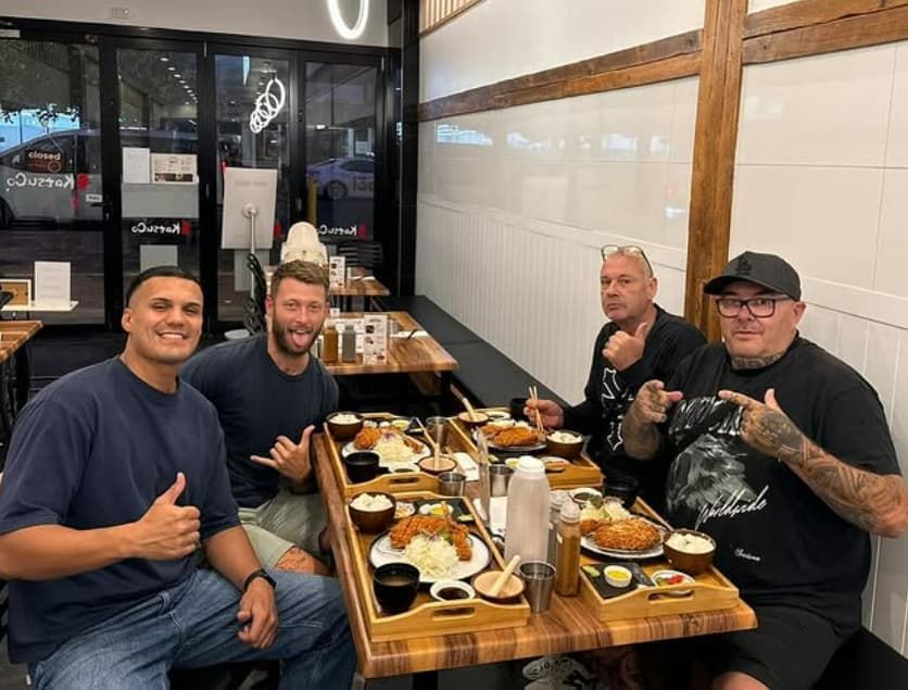 A Group of Men Are Sitting at a Table in a Restaurant Eating Food — Mentally Hooked in Helensvale, QLD