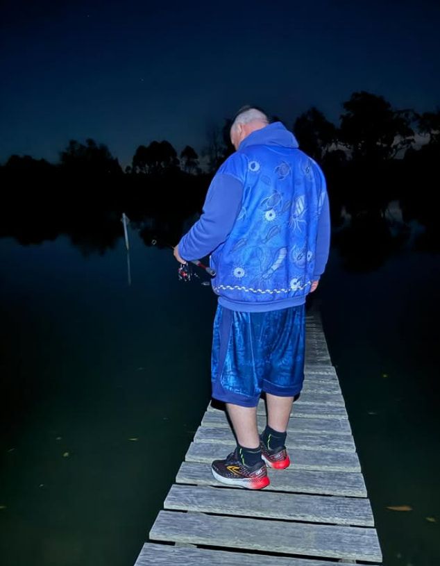 A Man in a Blue Jacket is Standing on a Dock Overlooking a Body of Water — Mentally Hooked in Helensvale, QLD