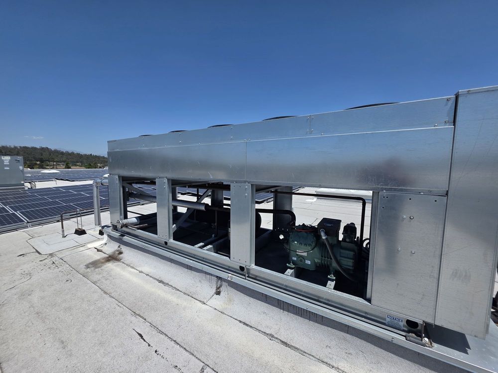 Snow-covered rooftop with a metal structure and large windows overlooking a winter landscape.