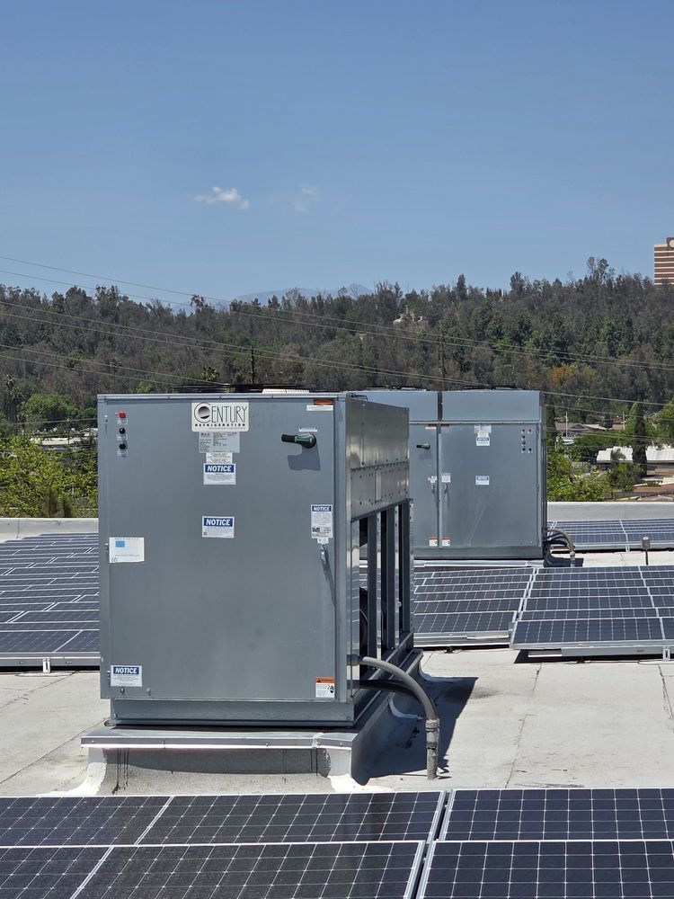 Gray rooftop HVAC units beside solar panels under a clear blue sky