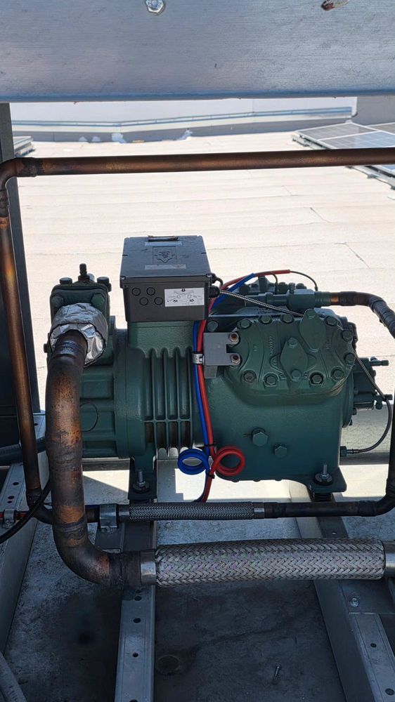 Industrial HVAC compressor and piping mounted in a metal frame outdoors.