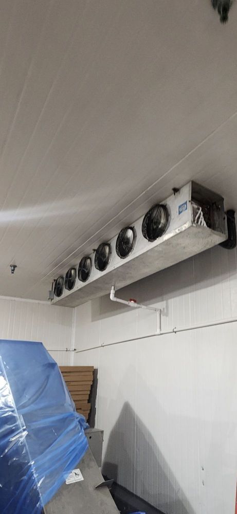 Wall-mounted cooling unit with multiple fans above a covered object in a tiled room