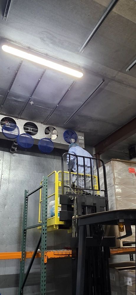 Industrial warehouse interior with metal platform, yellow railings, fans, and overhead lights