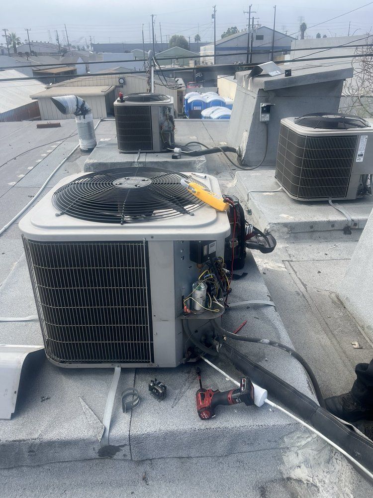 Roof-mounted HVAC units on a flat rooftop, with ducting and industrial equipment in view