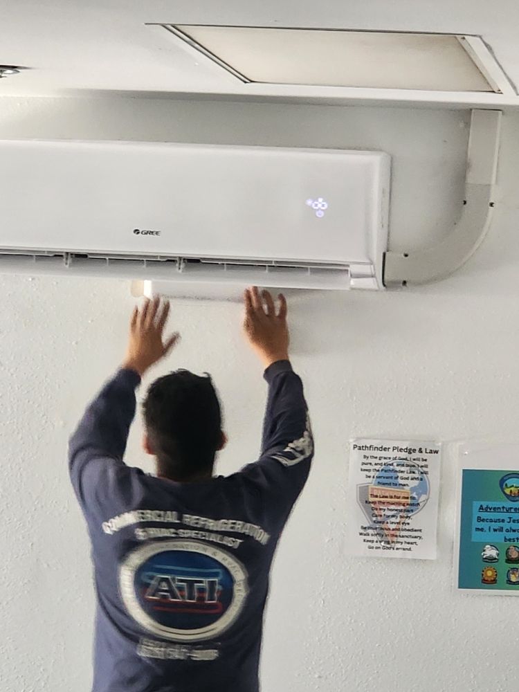 Technician installing a white wall-mounted air conditioner indoors