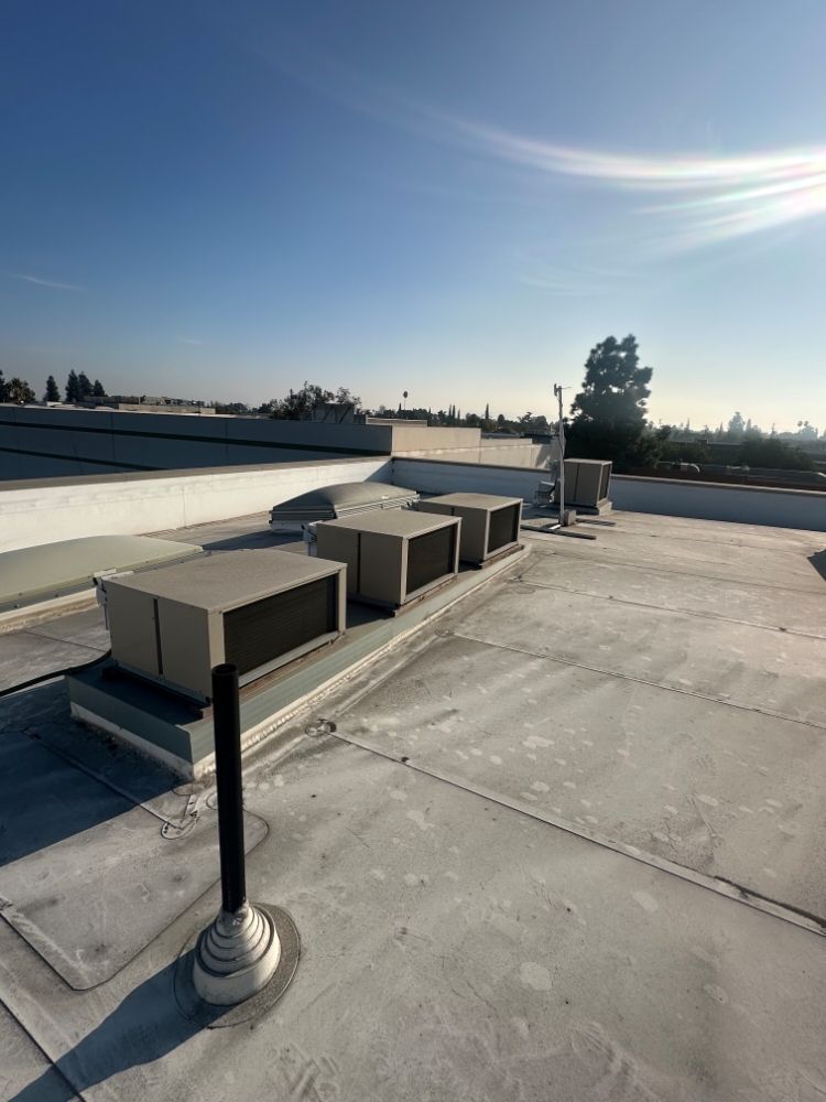 Flat rooftop with HVAC units and vents under a bright blue sky