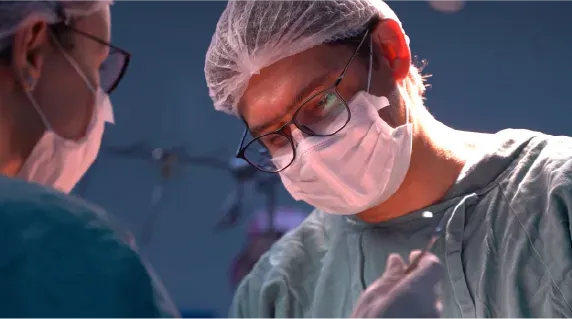 Um cirurgião usando máscara e óculos está operando um paciente.