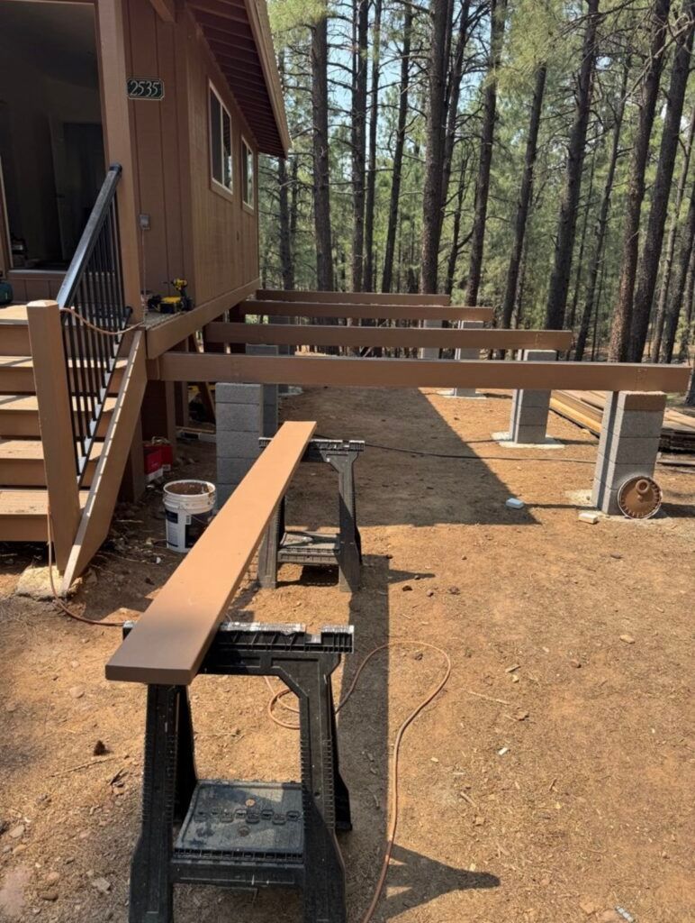 Wooden picnic tables beside a cabin in a pine forest clearing